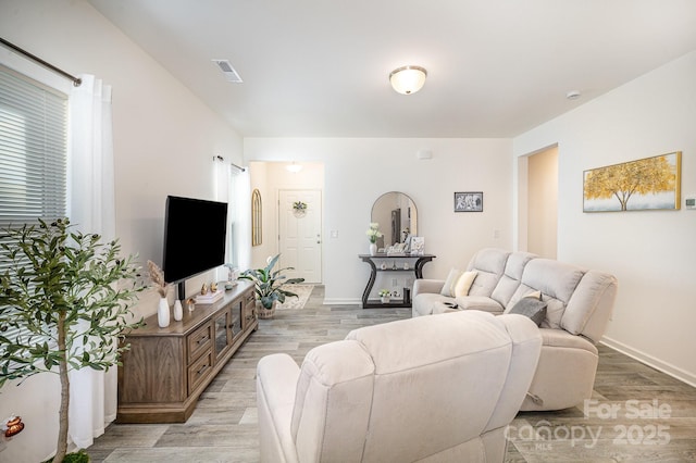 living area with light wood-style floors, visible vents, and baseboards