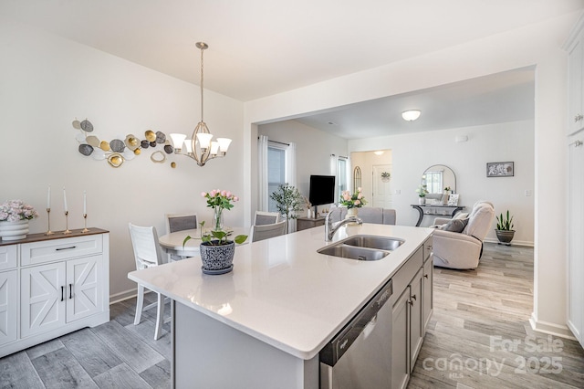 kitchen featuring open floor plan, dishwasher, light countertops, and a sink