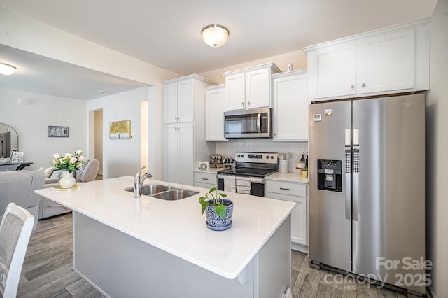 kitchen featuring backsplash, open floor plan, white cabinets, stainless steel appliances, and a sink