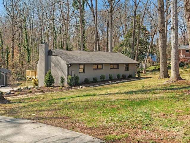 view of front of home featuring a shingled roof, a front lawn, and a chimney