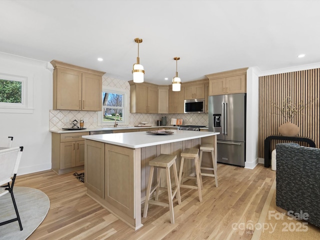 kitchen with a kitchen island, light brown cabinets, stainless steel appliances, and light wood-style floors