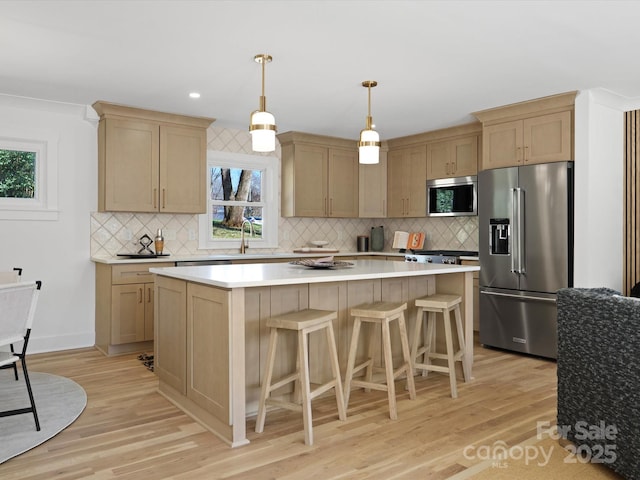 kitchen with light brown cabinets, light wood-style flooring, appliances with stainless steel finishes, and a kitchen island