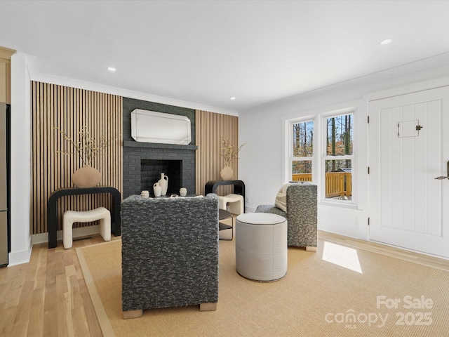 living room with recessed lighting, light wood-type flooring, a brick fireplace, and ornamental molding