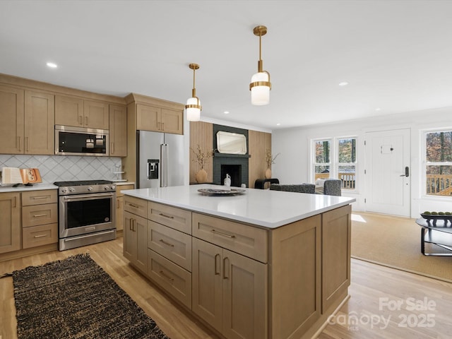 kitchen featuring light countertops, a fireplace, light wood-type flooring, and stainless steel appliances