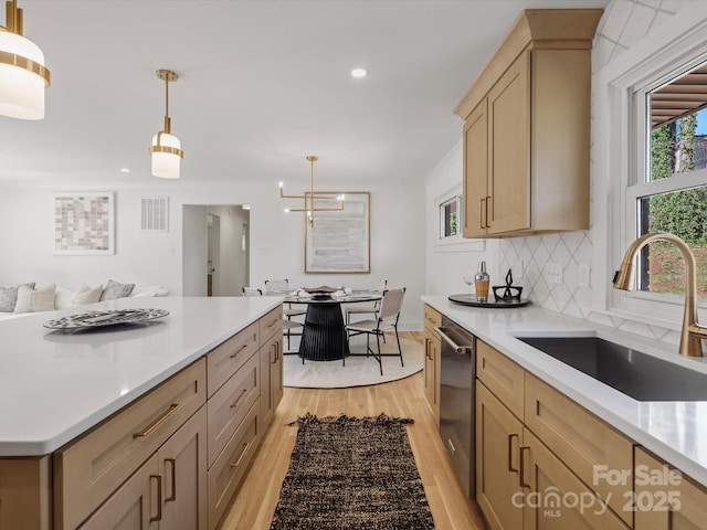 kitchen with dishwasher, a healthy amount of sunlight, light wood-style floors, and a sink