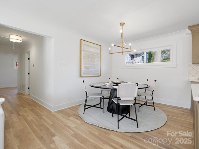 dining space with a notable chandelier, baseboards, crown molding, and light wood-style floors