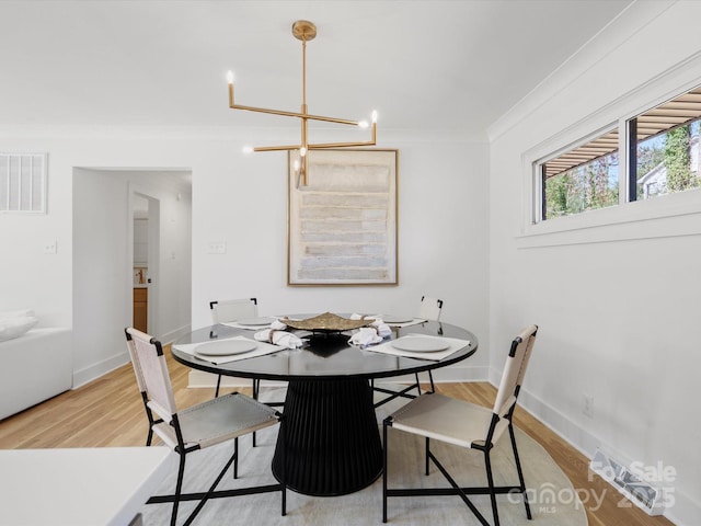 dining room featuring visible vents, light wood-style flooring, an inviting chandelier, crown molding, and baseboards