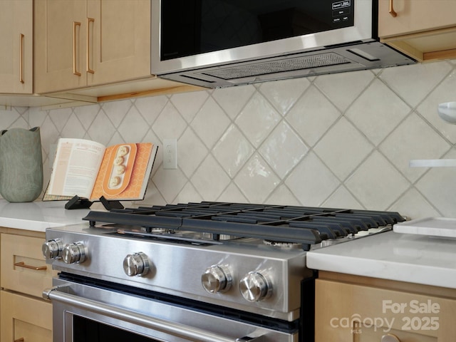 room details featuring light brown cabinetry, backsplash, stainless steel appliances, and light countertops