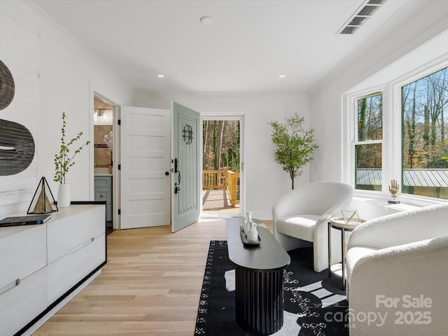 sitting room with recessed lighting, visible vents, crown molding, and light wood finished floors