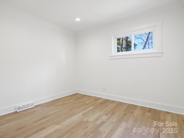 empty room featuring visible vents, baseboards, light wood-style flooring, and crown molding