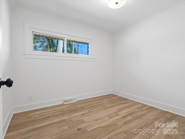 empty room featuring crown molding, baseboards, visible vents, and light wood-type flooring