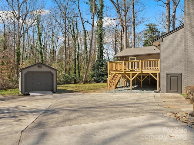 view of side of home with an outbuilding, a detached garage, driveway, and a wooden deck