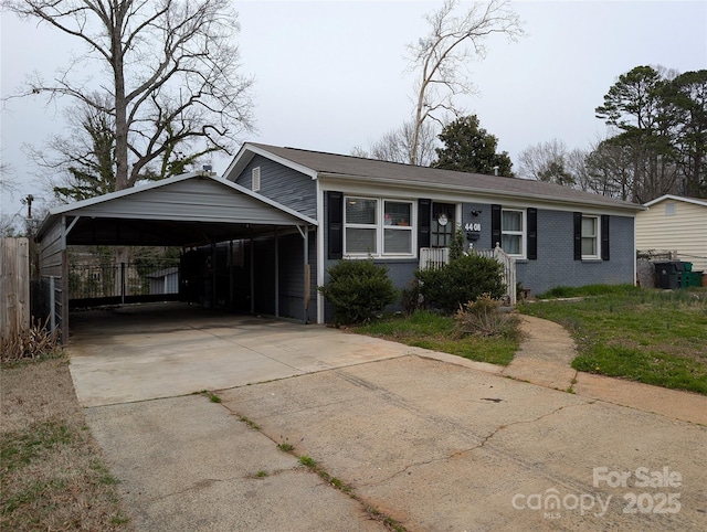 view of front of house with brick siding, fence, concrete driveway, and a detached carport