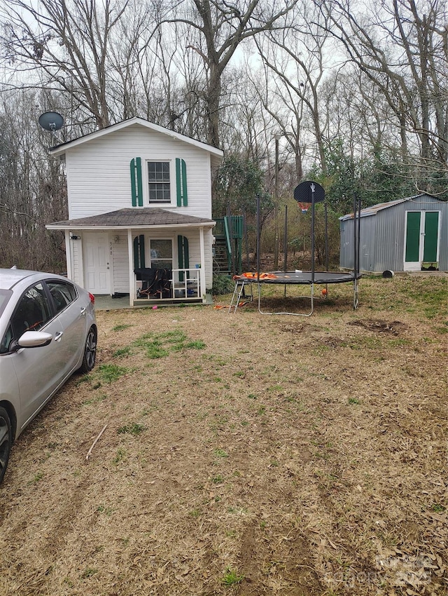 view of front of home with an outbuilding, a trampoline, and a front yard