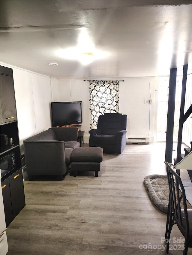 living area featuring baseboard heating, wood finished floors, floor to ceiling windows, and a decorative wall