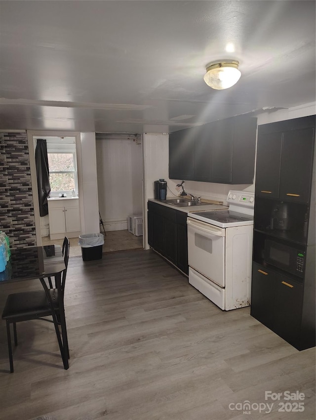 kitchen with light wood finished floors, dark cabinetry, black microwave, and electric stove