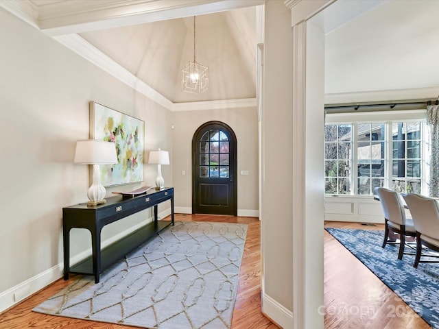 foyer featuring a chandelier, arched walkways, crown molding, and wood finished floors