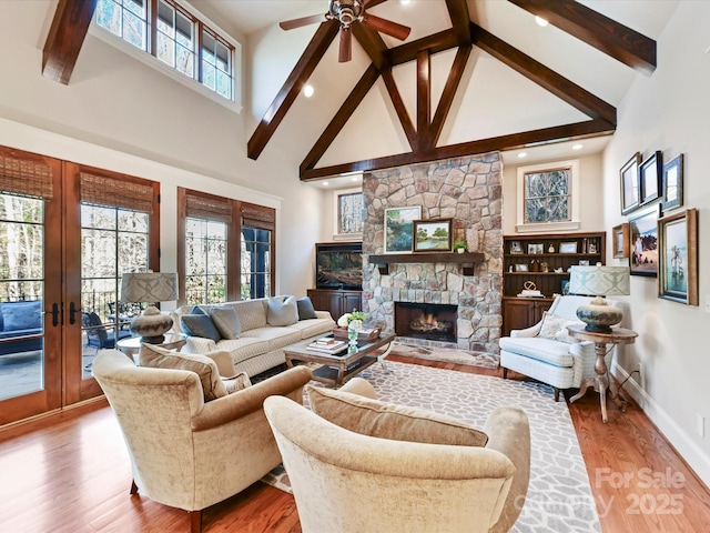 living room with plenty of natural light, high vaulted ceiling, wood finished floors, and a fireplace