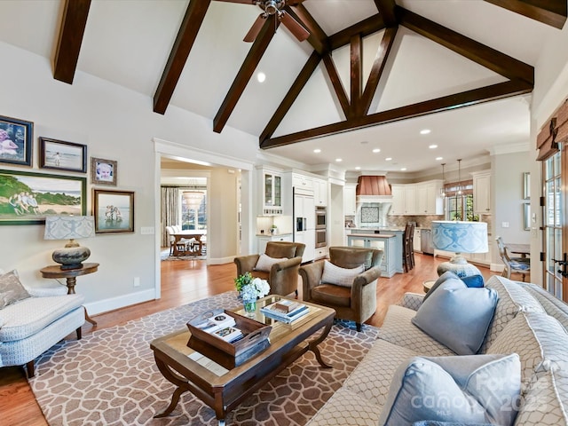 living room with beam ceiling, light wood-style flooring, high vaulted ceiling, and baseboards