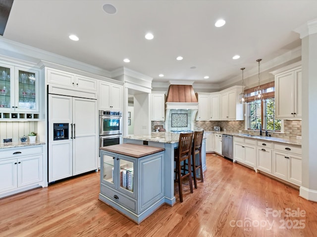 kitchen with a center island, a breakfast bar area, custom range hood, stainless steel appliances, and a sink