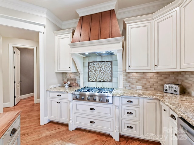 kitchen with light wood-type flooring, ornamental molding, custom range hood, white cabinetry, and stainless steel gas cooktop