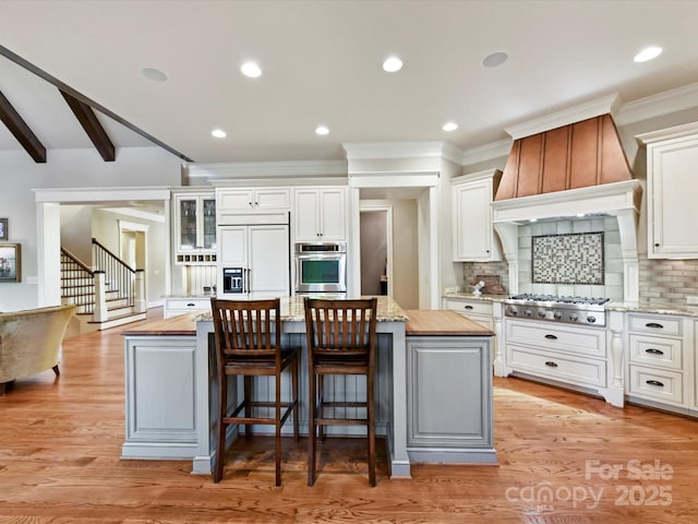 kitchen featuring stainless steel appliances, white cabinets, a center island, and light wood finished floors