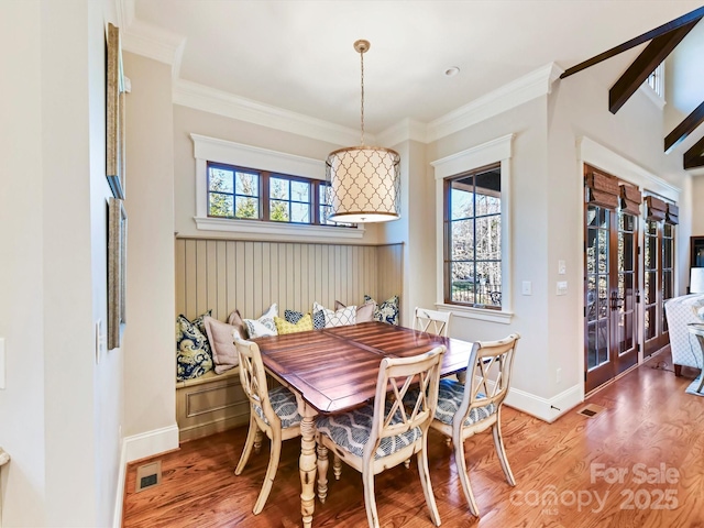 dining area featuring wood finished floors, baseboards, a wealth of natural light, and ornamental molding