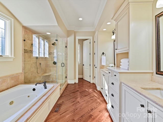 full bath with a wealth of natural light, ornamental molding, wood finished floors, a shower stall, and vanity