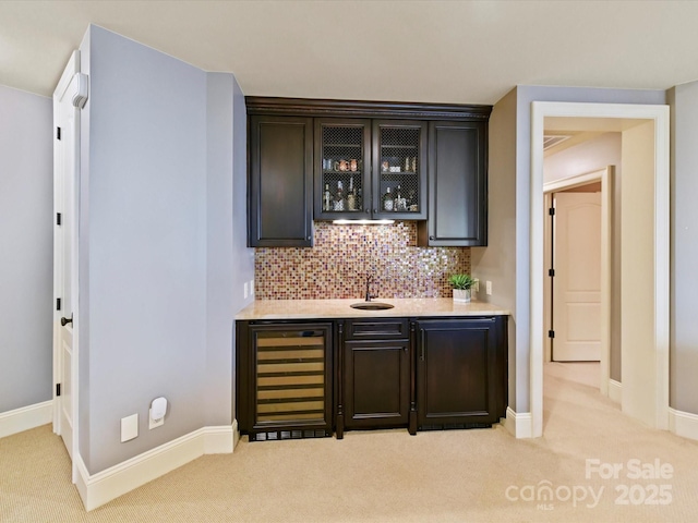 bar featuring beverage cooler, wet bar, a sink, light carpet, and tasteful backsplash