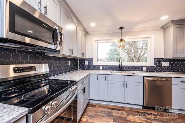 kitchen featuring gray cabinets, a sink, light stone counters, appliances with stainless steel finishes, and decorative backsplash