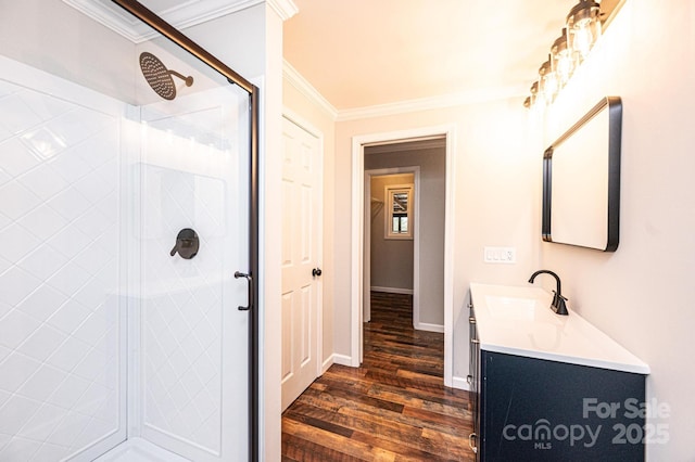 bathroom with vanity, wood finished floors, baseboards, a stall shower, and crown molding