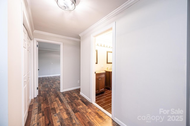 corridor featuring dark wood finished floors, crown molding, and baseboards