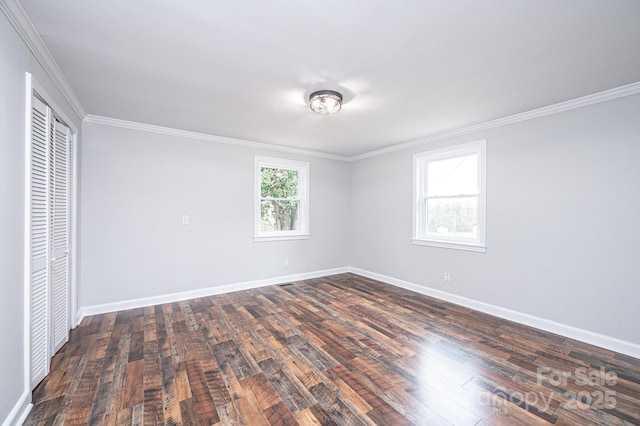 unfurnished bedroom featuring dark wood-style floors, baseboards, crown molding, and a closet