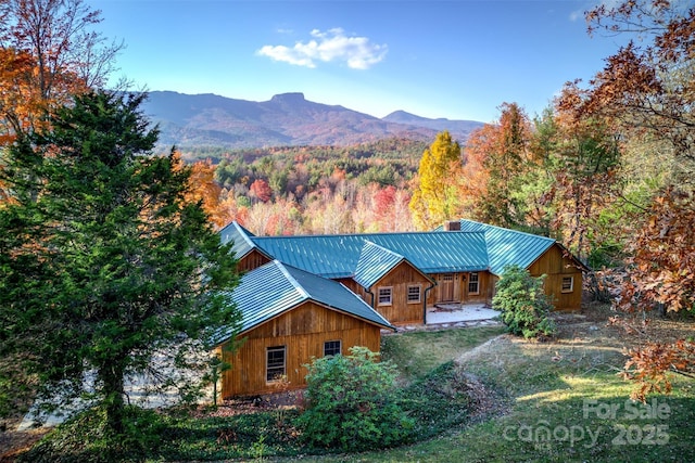 exterior space featuring a mountain view, metal roof, a standing seam roof, and a view of trees