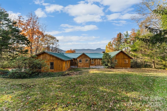 rear view of house with metal roof and a lawn