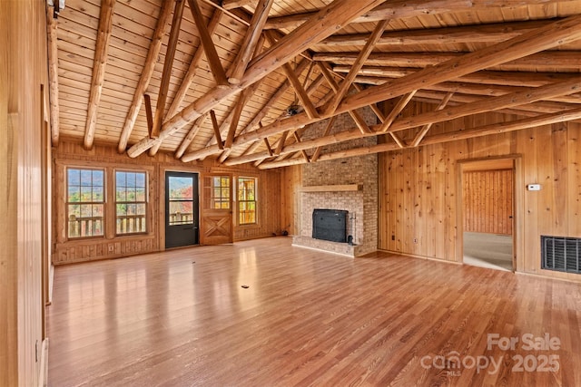 unfurnished living room featuring visible vents, wood finished floors, wooden walls, a fireplace, and wood ceiling