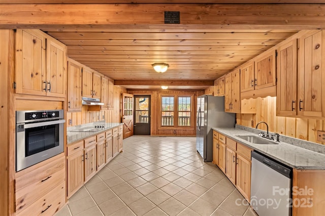 kitchen featuring light brown cabinets, under cabinet range hood, light tile patterned floors, appliances with stainless steel finishes, and a sink