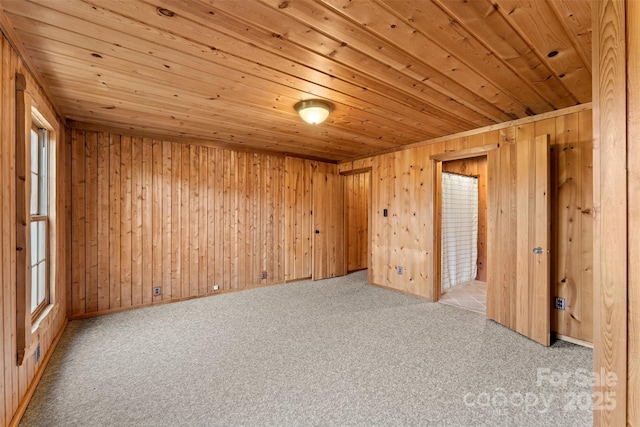 carpeted spare room with wooden walls and wooden ceiling