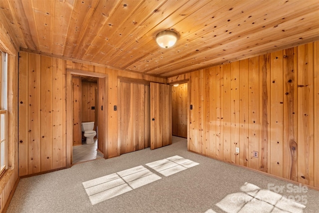 carpeted spare room with wooden walls and wooden ceiling