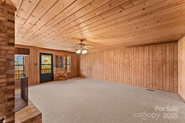 unfurnished living room with wooden ceiling, carpet, and wood walls