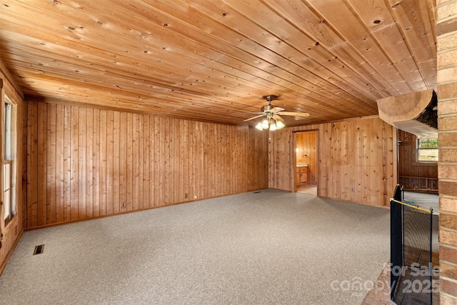 unfurnished living room featuring visible vents, carpet, wood ceiling, and wood walls