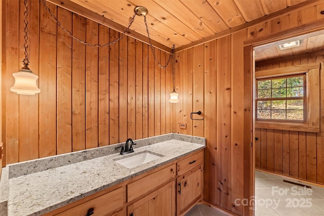 bathroom featuring tile patterned flooring, wood walls, wooden ceiling, and vanity