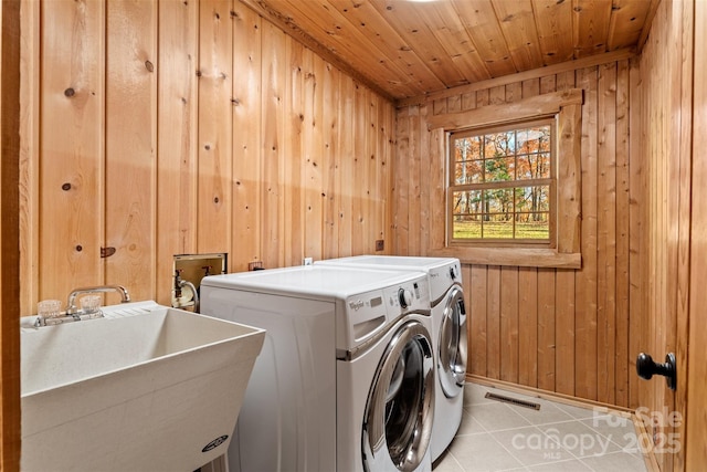 laundry area featuring light tile patterned floors, laundry area, a sink, wood ceiling, and washer and clothes dryer