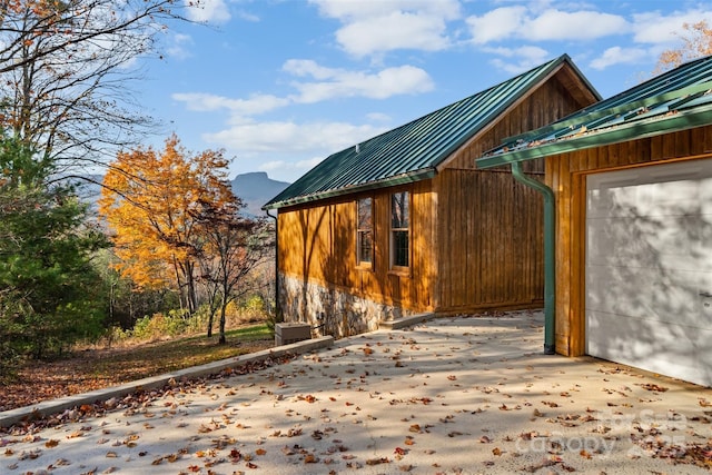 view of property exterior featuring concrete driveway, metal roof, and a garage