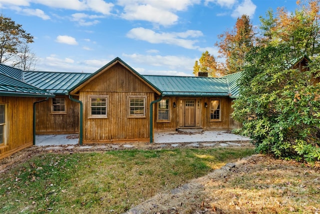 rear view of house featuring a chimney, metal roof, and a standing seam roof