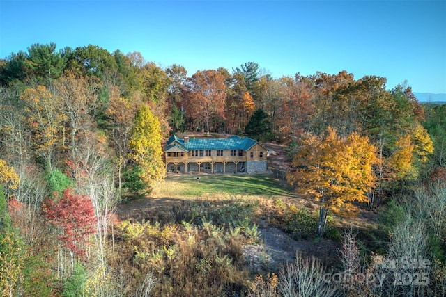 back of property featuring a lawn and a view of trees