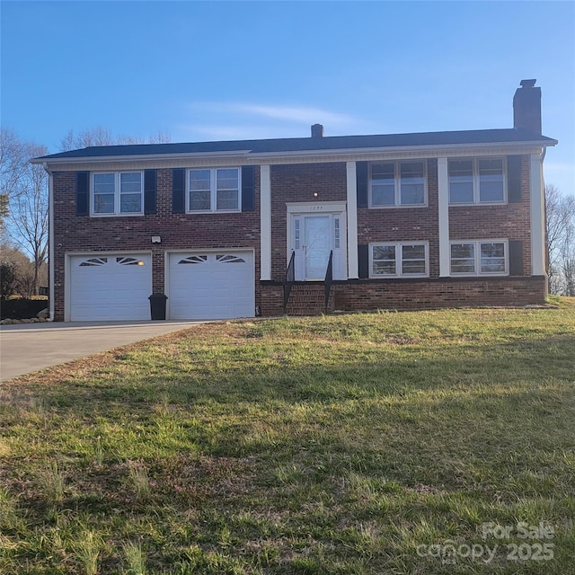 split foyer home featuring concrete driveway, brick siding, an attached garage, and a front yard