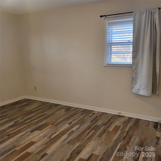 unfurnished room featuring dark wood-style flooring and baseboards