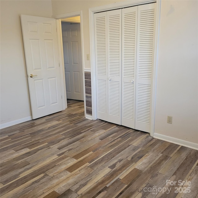 unfurnished bedroom featuring a closet, wood finished floors, and baseboards