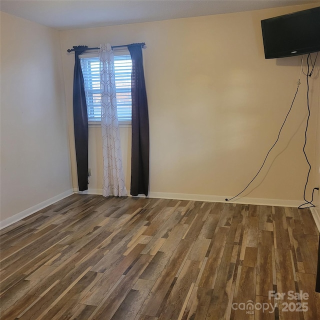 unfurnished room featuring baseboards and wood finished floors